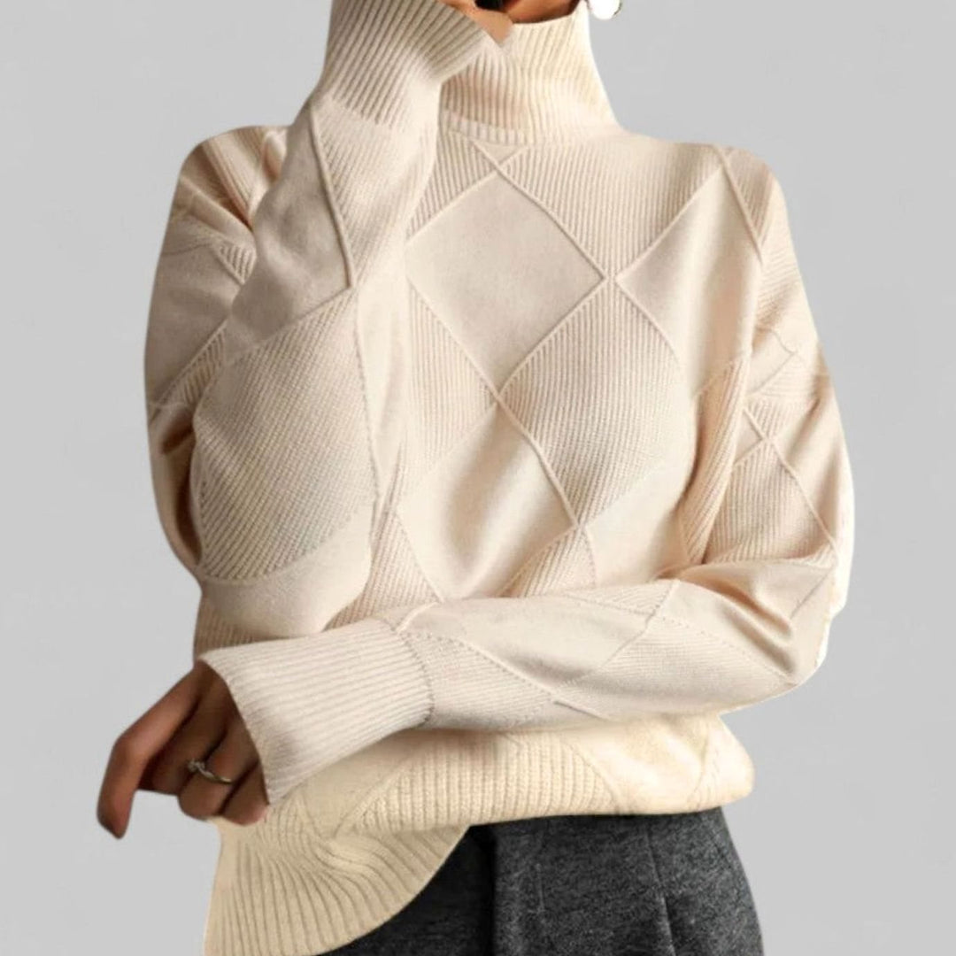 Cream oversized turtleneck sweater with a diamond knit pattern, worn with grey trousers