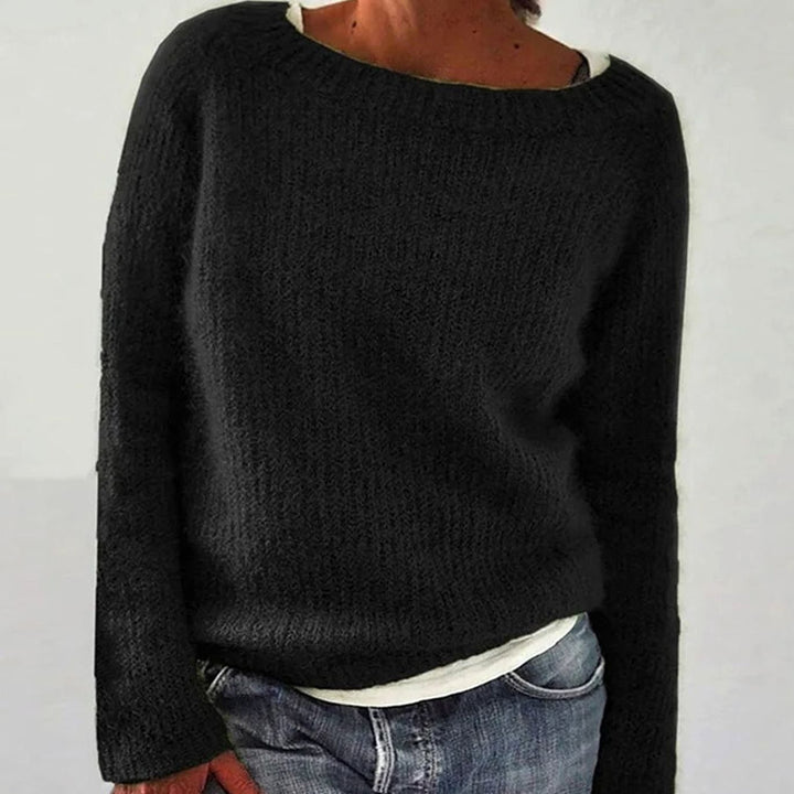 Black boat neck knit sweater worn loose over a white top and jeans