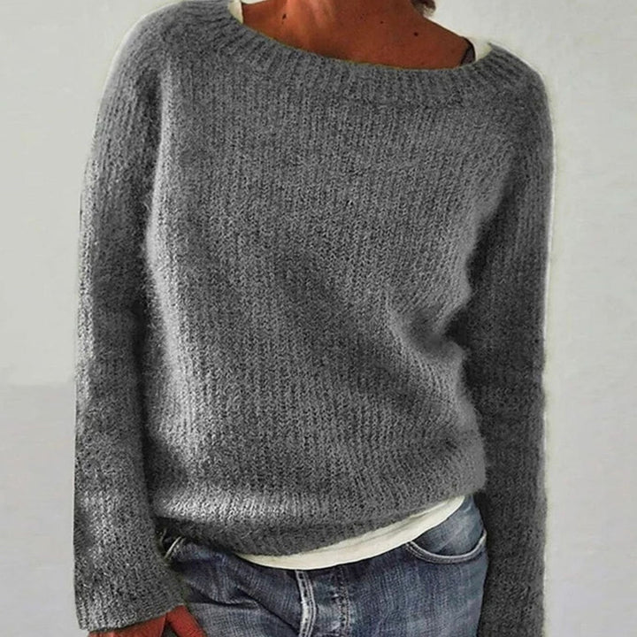 Grey relaxed fit boat neck knit sweater worn over a white top and jeans