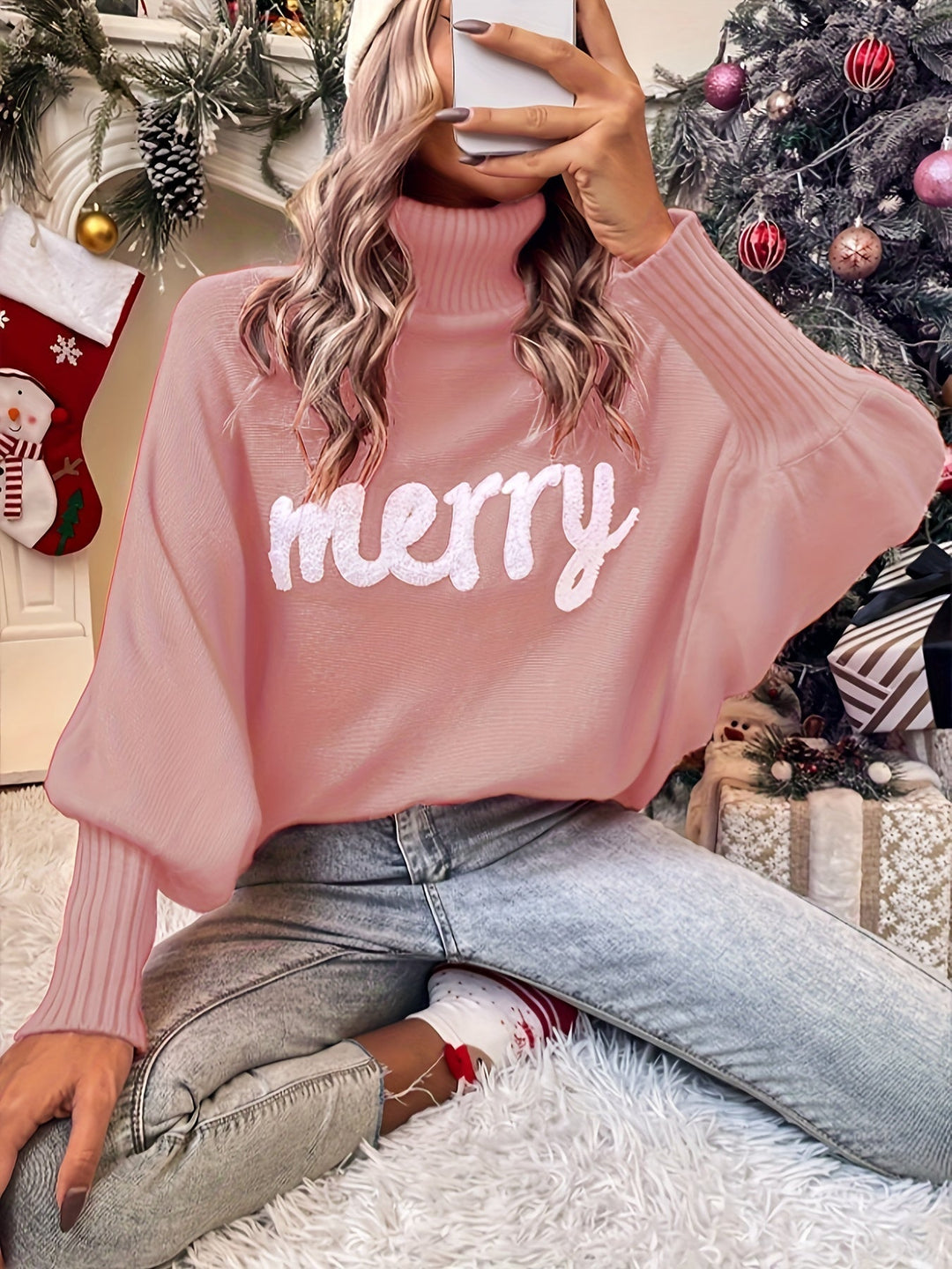 Pink turtleneck sweater with batwing sleeves and white textured merry lettering