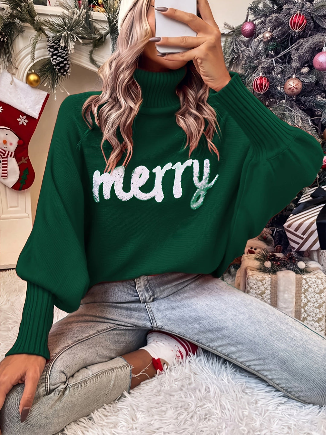 Green turtleneck sweater with batwing sleeves and white merry lettering, worn with jeans