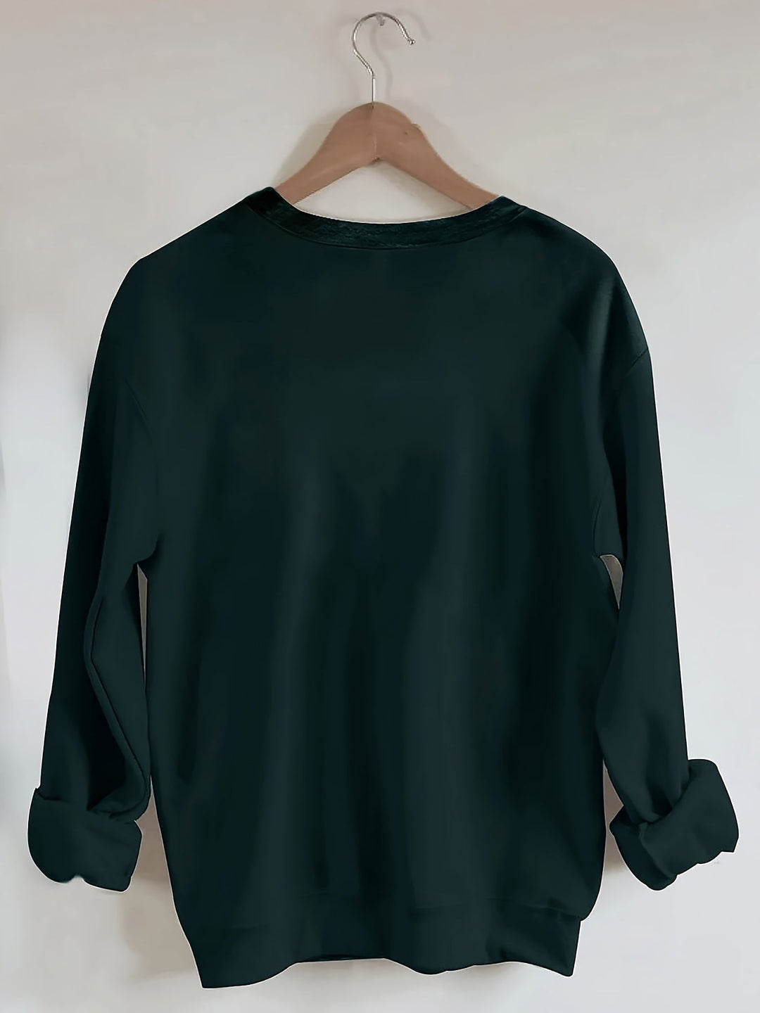 Back of a dark green crew neck sweatshirt on a wooden hanger, plain knit