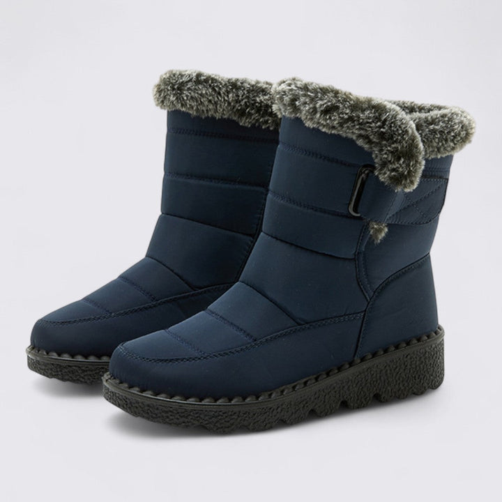 Pair of navy padded snow boots with faux fur cuff and grip sole