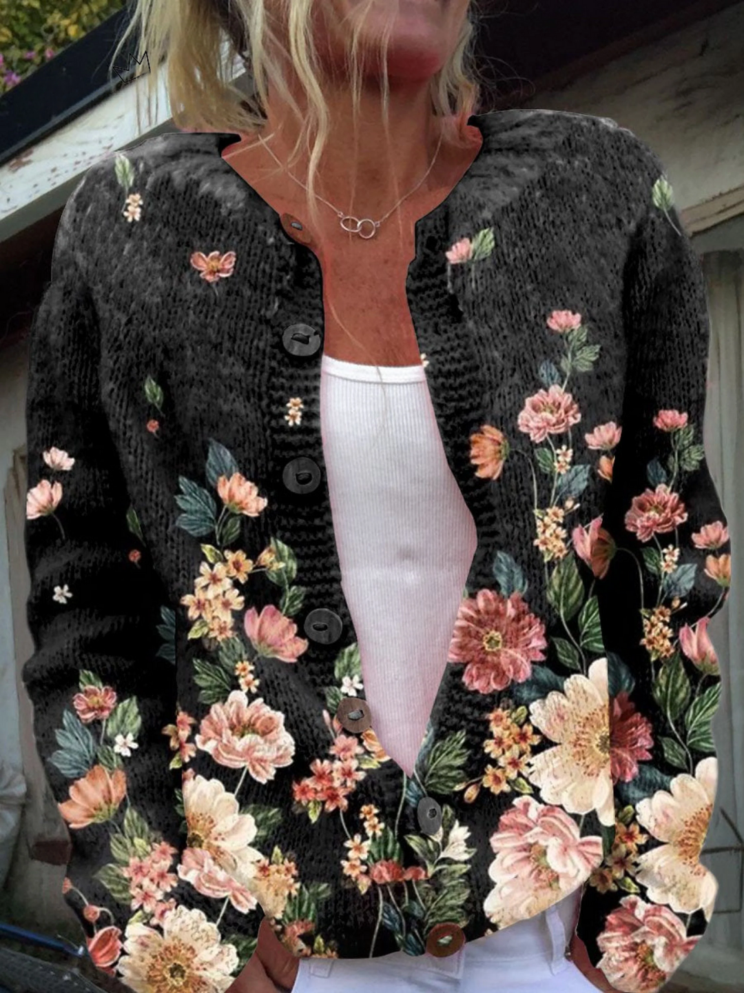 Black button front cardigan with a pink and cream floral border print, worn open over a white top