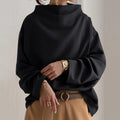 Black funnel neck dolman top worn with camel wide pants, front view