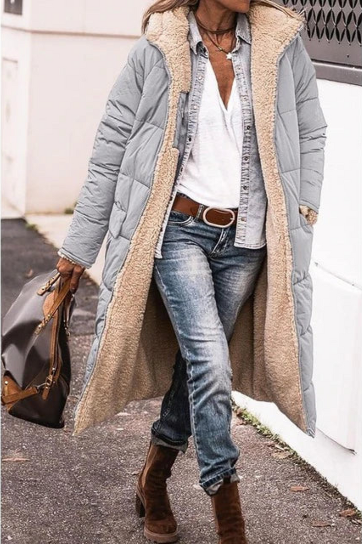 Woman wearing a light grey longline coat with cream sherpa lining, worn open