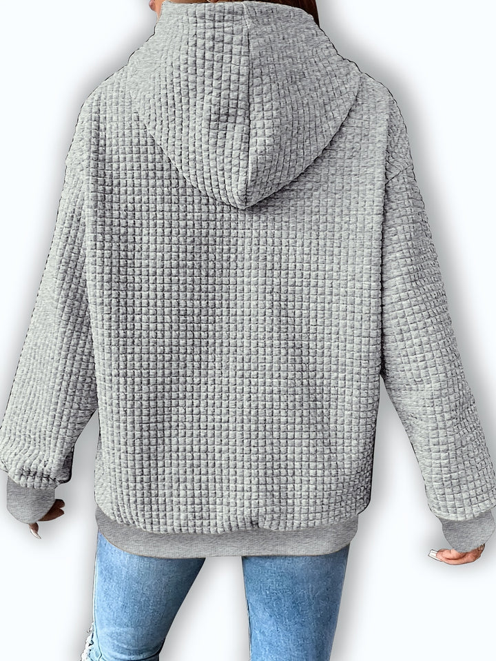 Back view of a light grey waffle textured hoodie with a relaxed fit and ribbed cuffs and hem