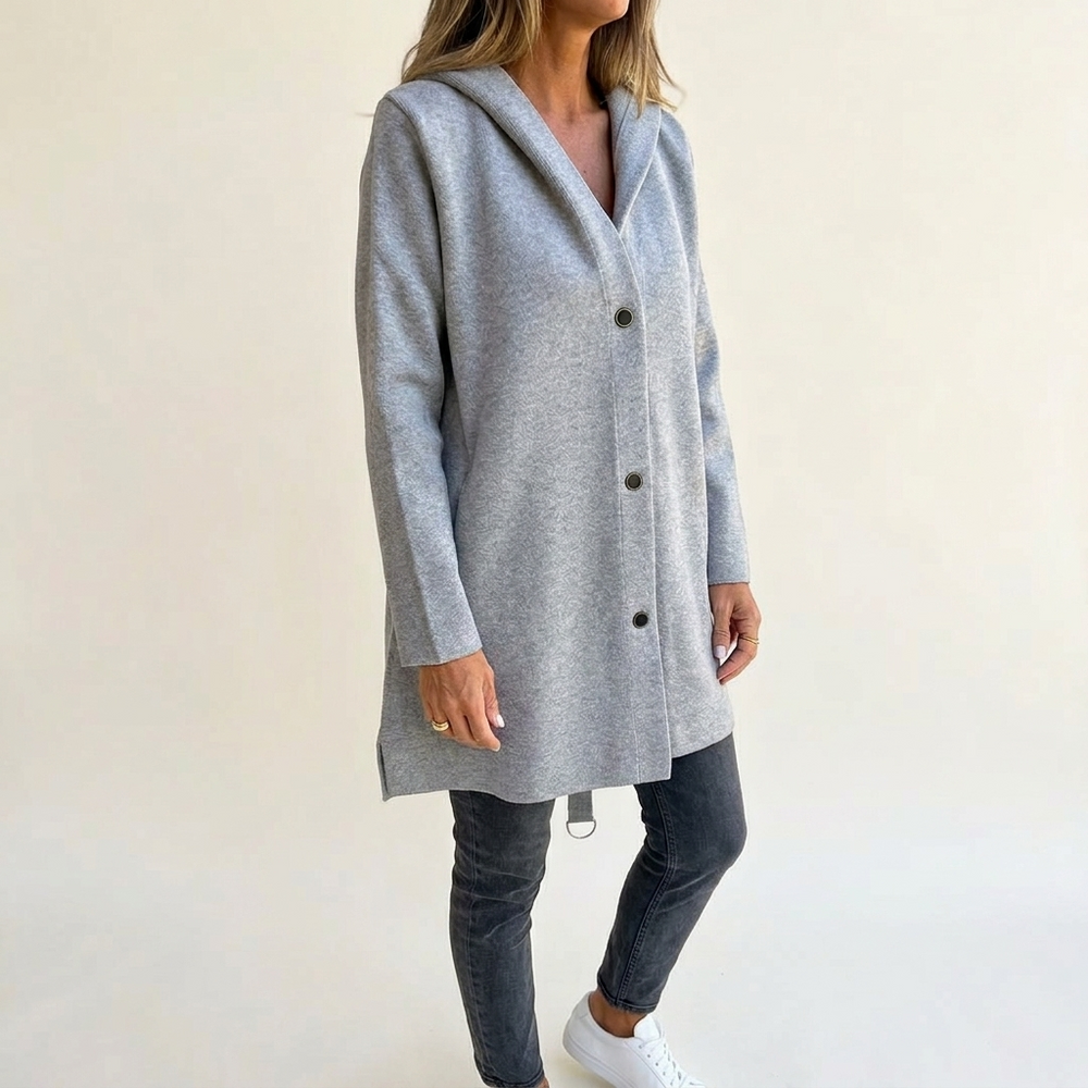 Woman in a light grey longline hooded cardigan jacket buttoned over grey jeans