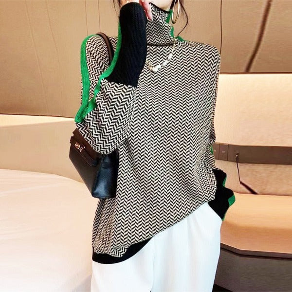 Black and white herringbone turtleneck sweater with green trim worn with white trousers