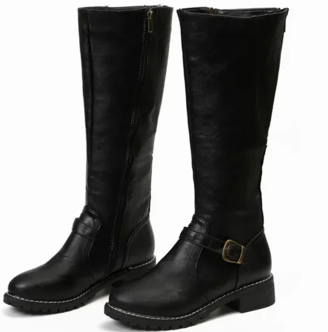 Pair of black knee high leather boots with ankle buckle strap and lug sole