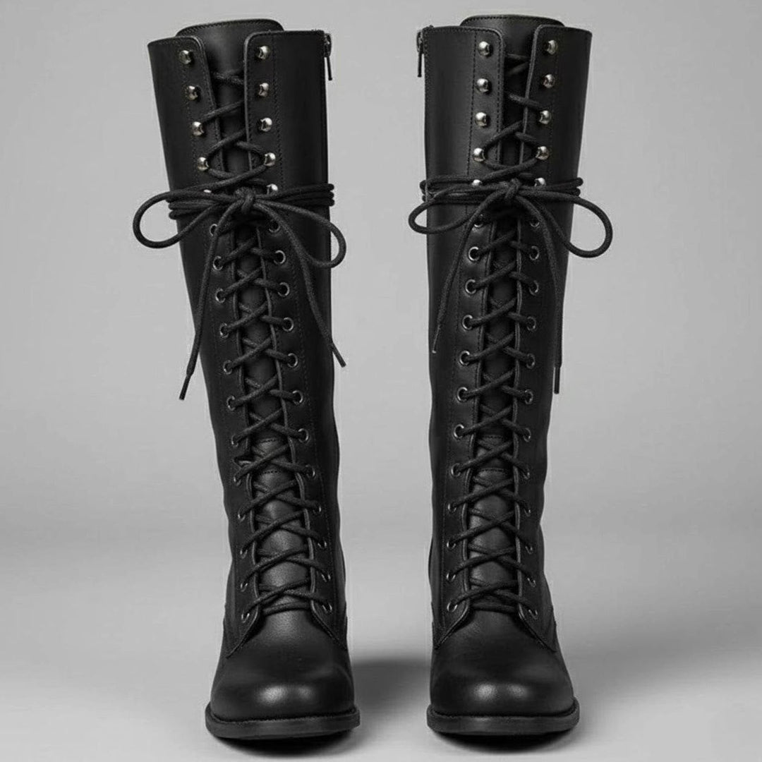 Pair of black lace up knee high combat boots with studded shafts, front view