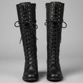 Pair of black lace up knee high combat boots with studded shafts, front view