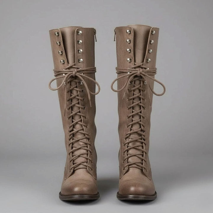 Pair of taupe leather lace up knee high boots with studded shafts, front view