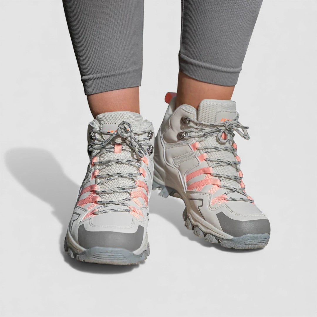Grey and pink lace up hiking shoes with rugged non slip soles, worn with grey leggings, front view