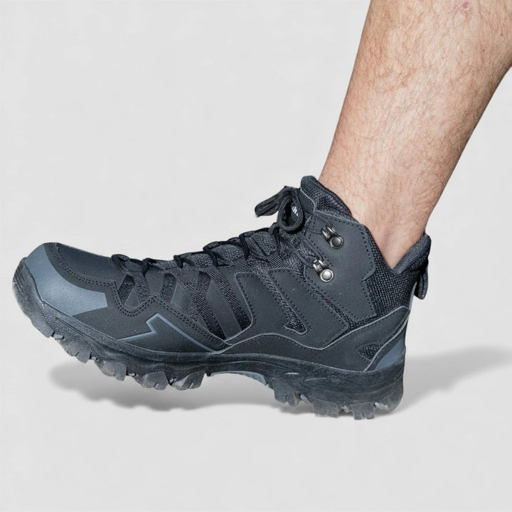 Side view of a black lace up hiking shoe with grey overlays and a deep lug sole