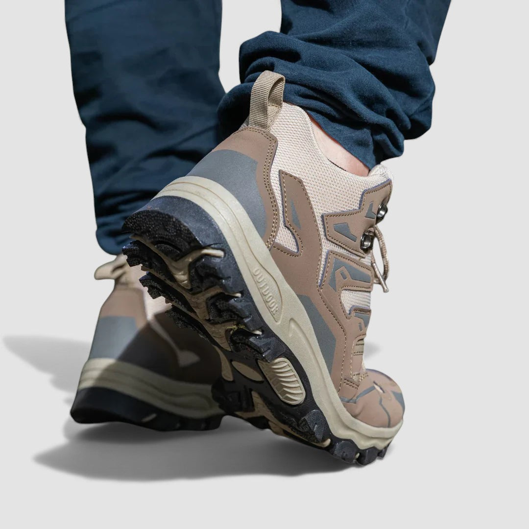 Beige hiking shoes seen from behind with one heel lifted to show the lug sole