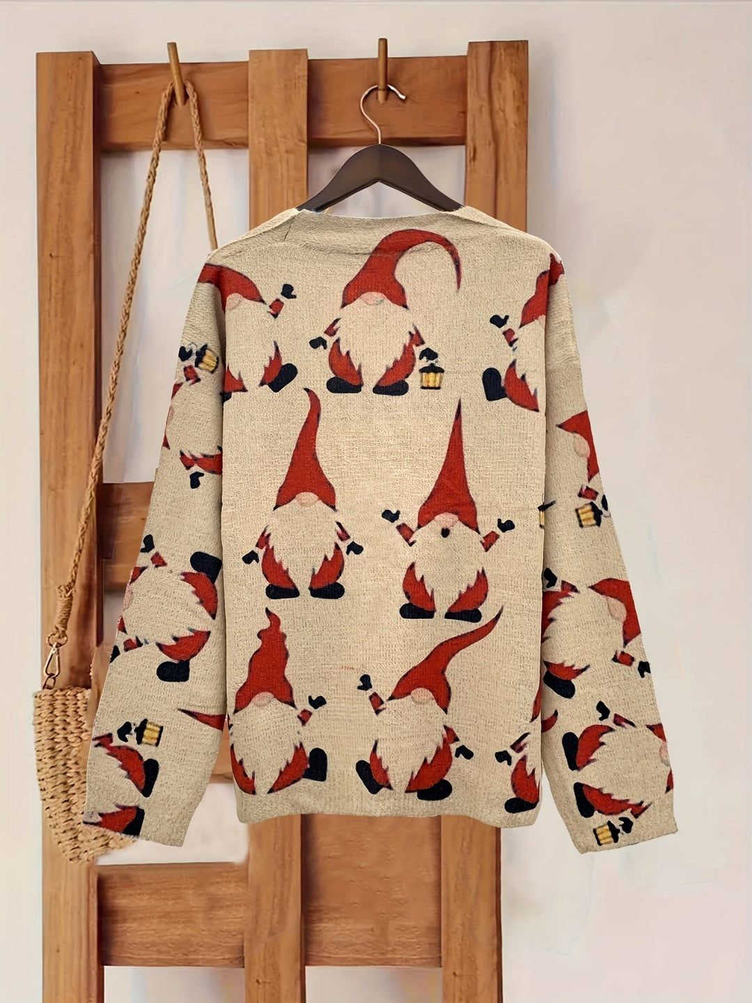Back of a beige long sleeve cardigan with red and black gnome print, shown on a wooden hanger