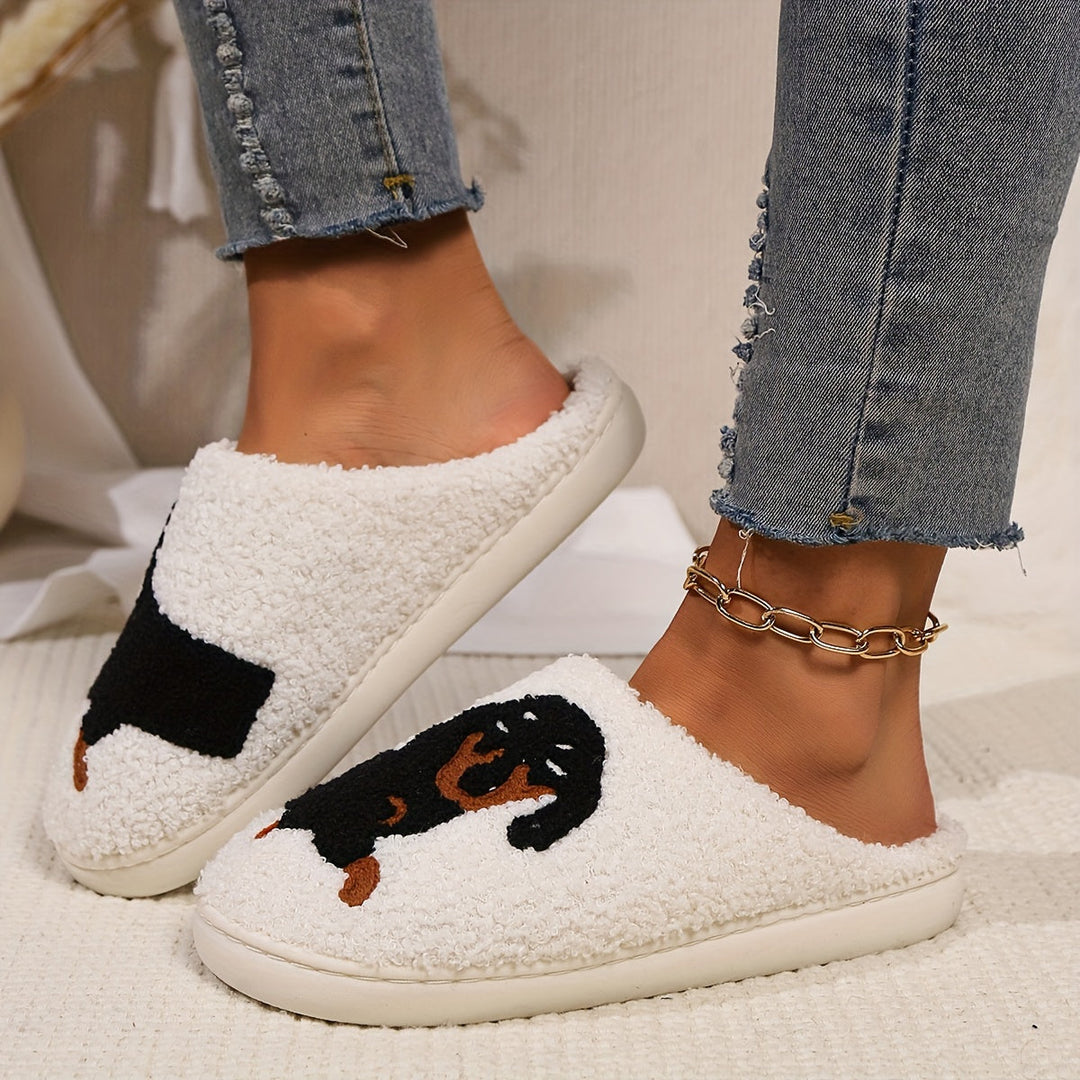 White fuzzy house slippers with a black and tan dachshund motif, worn with cropped jeans