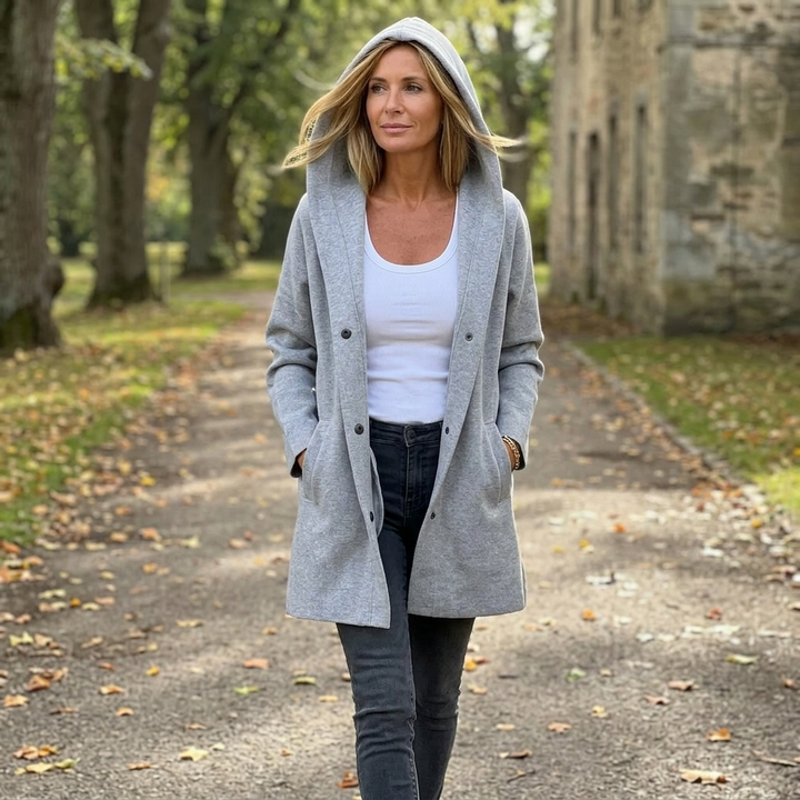 Woman walking outdoors in a grey longline hooded cardigan jacket worn open over a white tank top
