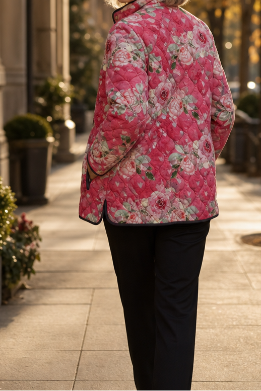 Back view of a pink rose print quilted jacket on a garden path