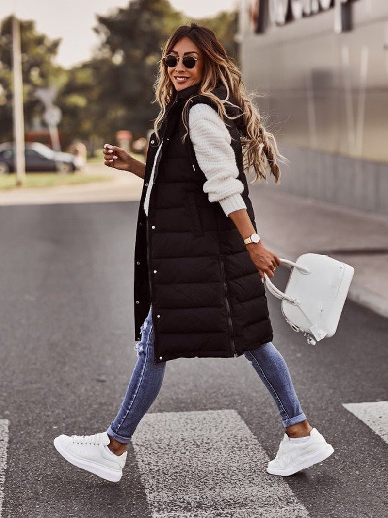 Black longline hooded puffer vest with skinny jeans, walking front view