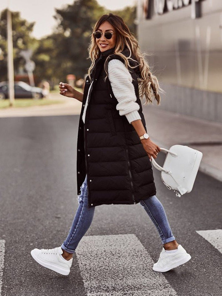 Black longline hooded puffer vest with skinny jeans, walking front view