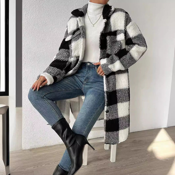 Black and white teddy check coat with blue jeans, seated front view