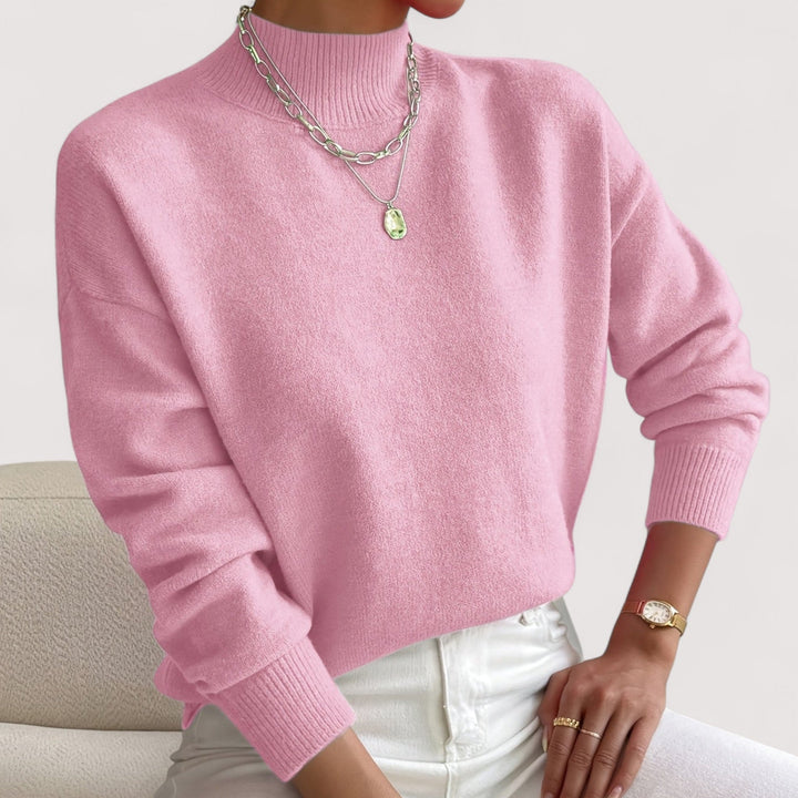 Woman wearing a soft pink mock neck knit sweater with ribbed cuffs