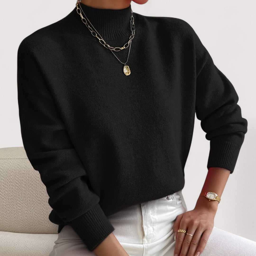 Black mock neck knit sweater with ribbed cuffs, worn with white jeans
