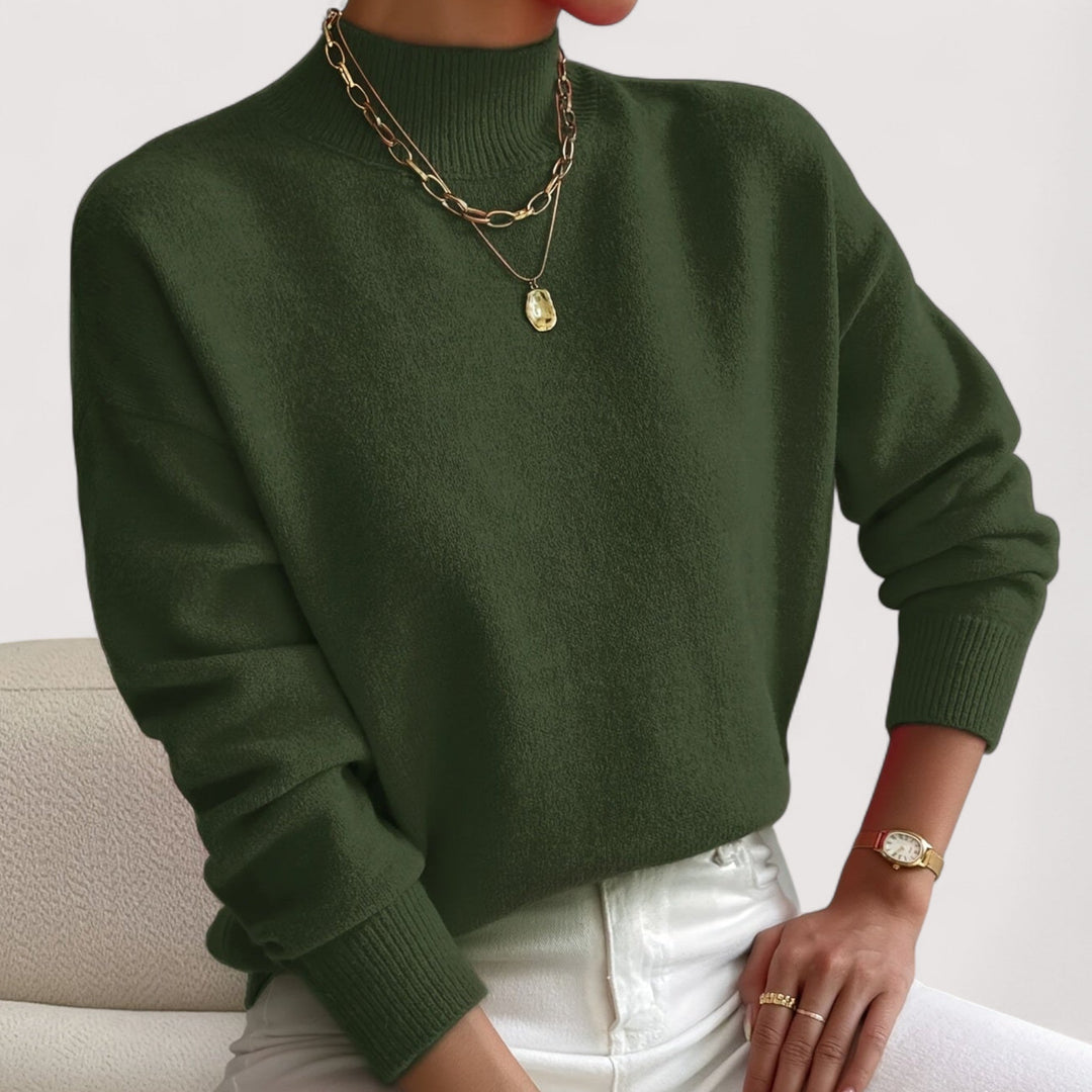 Olive green mock neck knit sweater with ribbed cuffs, worn with white jeans