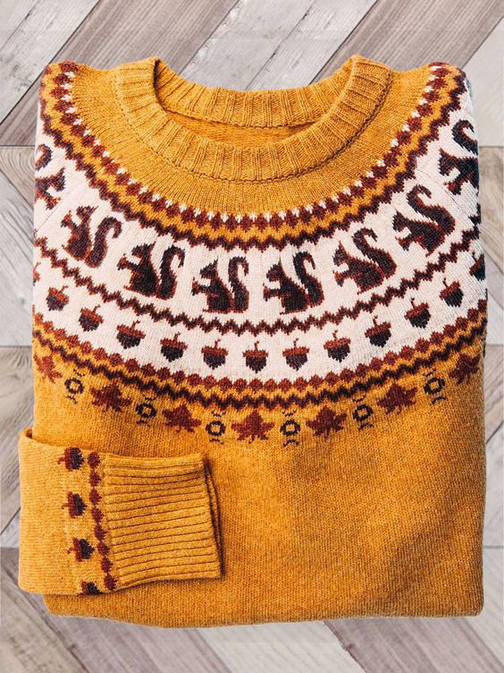 Folded mustard yellow knit sweater with a cream yoke of squirrels and acorns in brown and red