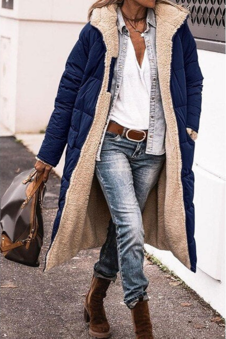 Woman in a navy longline quilted coat with cream faux shearling lining, worn open outdoors