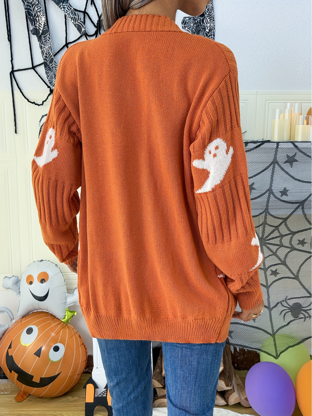 Back view of an orange ribbed cardigan with white ghost motifs on the sleeves