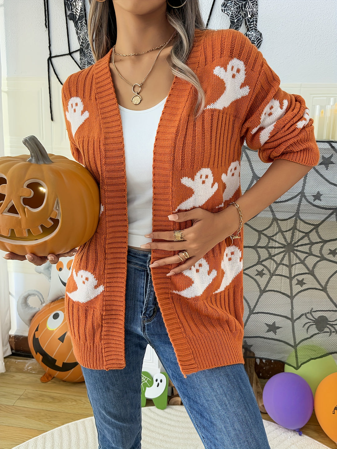Orange ribbed open front cardigan with white ghost motifs, worn with jeans