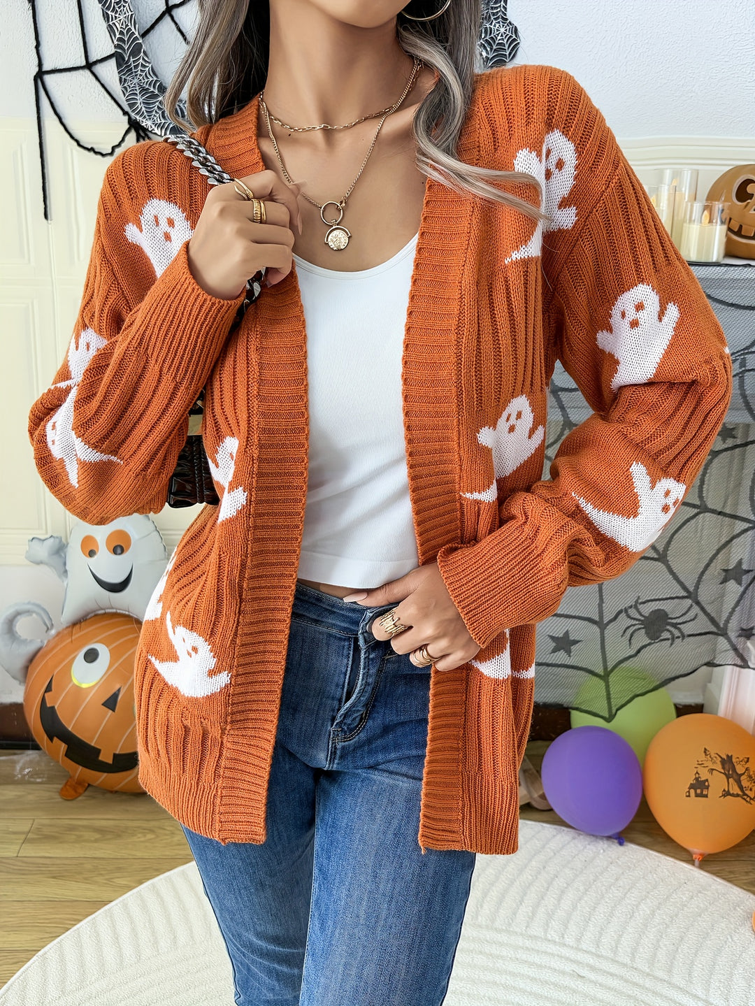 Orange ribbed knit cardigan with white ghost motifs, worn open over a white top