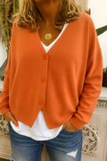 Close up of a rust orange V neck button front cardigan worn over a white tee