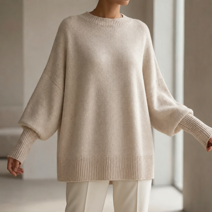 Model wearing an oversized beige crew neck sweater with ribbed cuffs and hem
