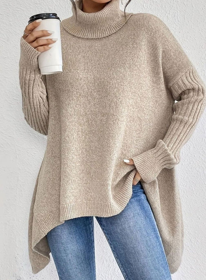 Beige oversized longline turtleneck sweater with ribbed cuffs and side slit, worn with jeans