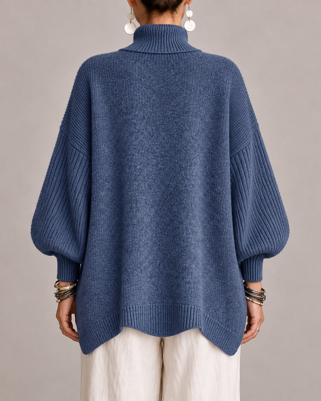 Back view of the blue turtleneck sweater with its longer curved hem