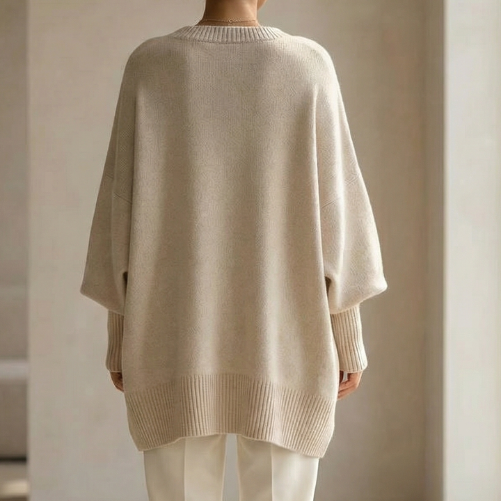 Back view of an oversized beige knit sweater with ribbed cuffs and hem
