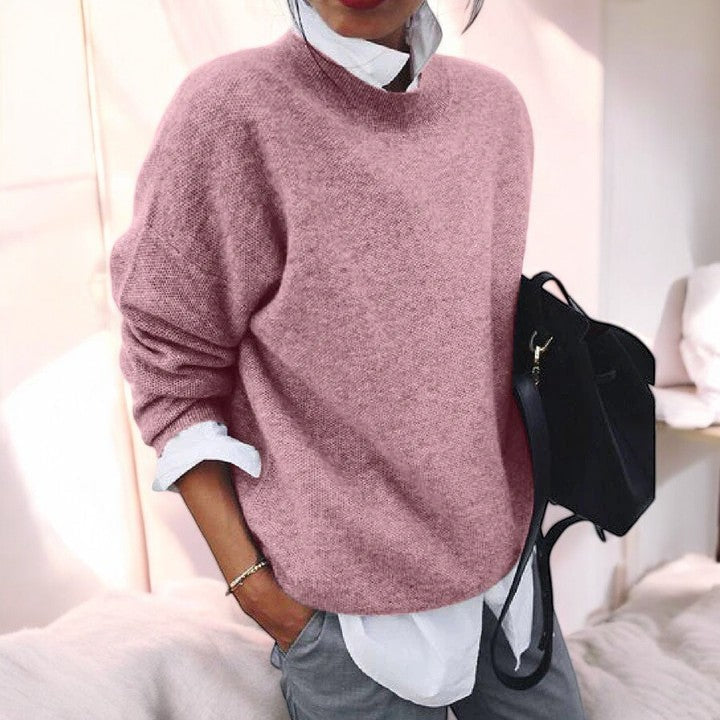 Woman in a dusty pink drop shoulder knit sweater layered over a white shirt