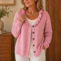 Pink knit cardigan with ruffle trimmed V neckline and brown buttons, front view