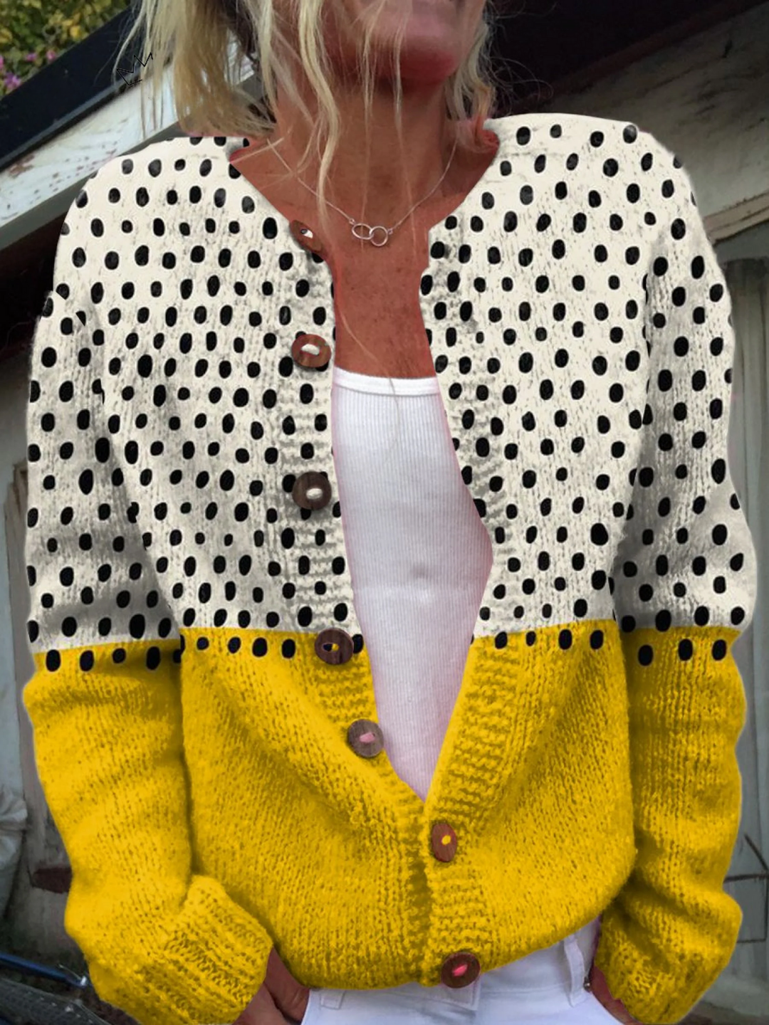 Knit cardigan with a black dotted cream top half and a solid yellow lower half, worn open