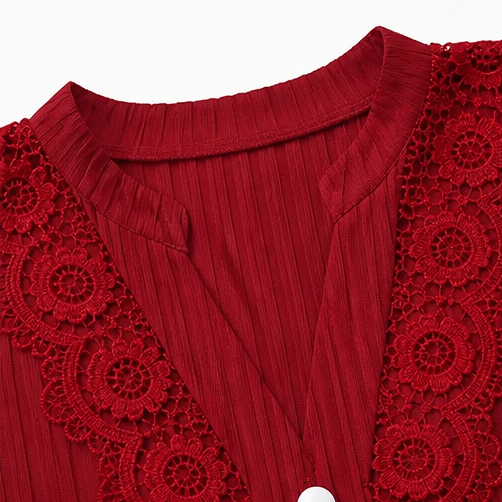 Close up of the red V neckline and floral lace trim on a pleated top