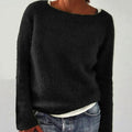 Black boat neck knit sweater worn loose over a white top and jeans