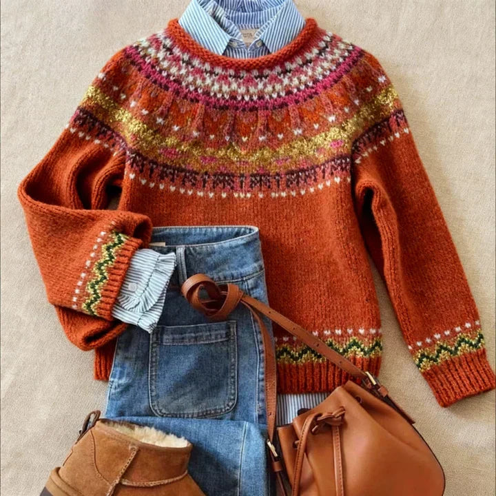Rust knit sweater with a patterned yoke, laid flat with jeans