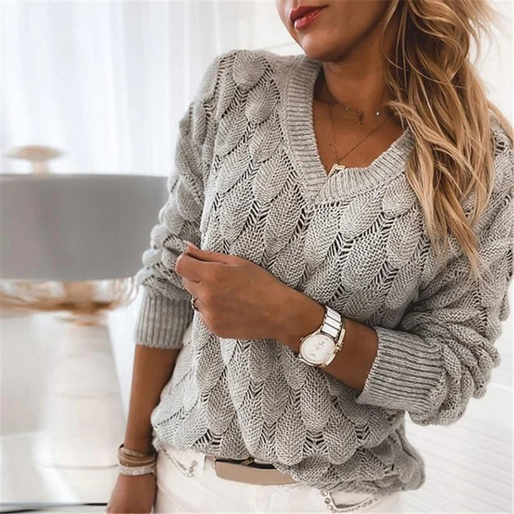 Grey scalloped pointelle knit V-neck sweater worn over white jeans, front view