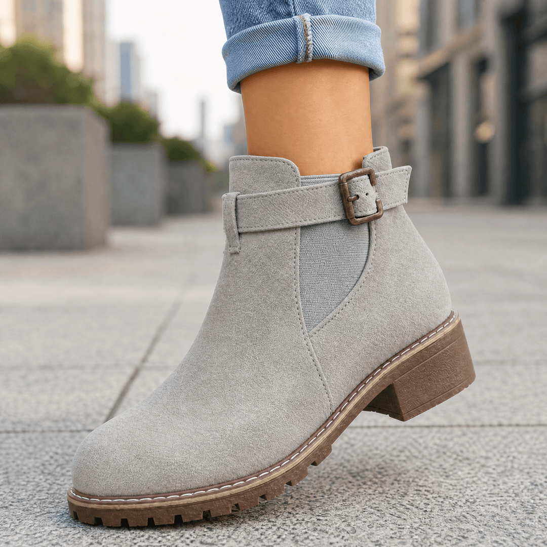 Grey suede buckle strap ankle boots with a brown block heel worn with cuffed jeans