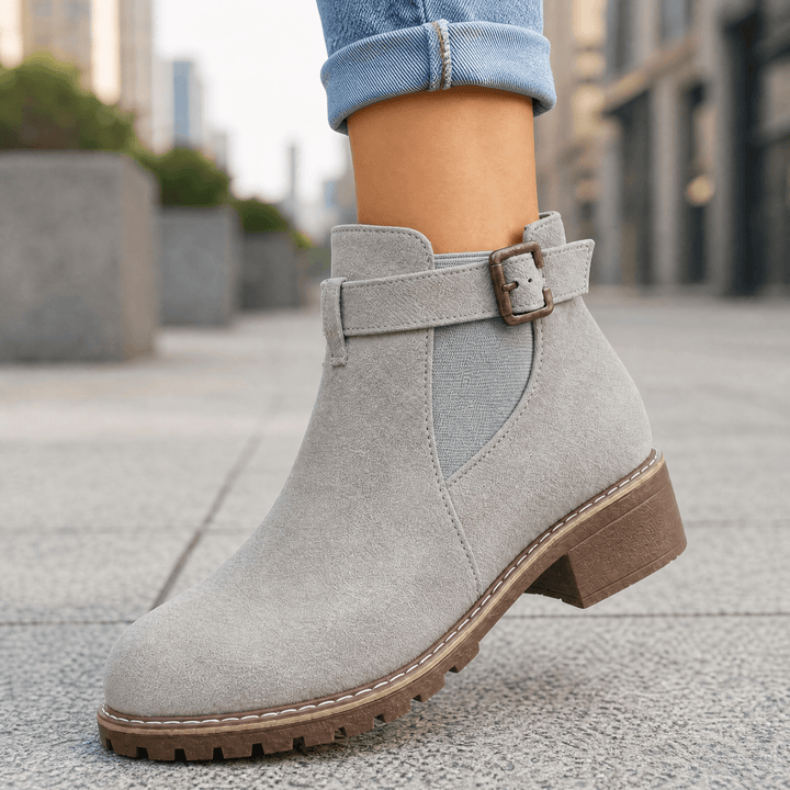 Grey suede buckle strap ankle boots with a brown block heel worn with cuffed jeans