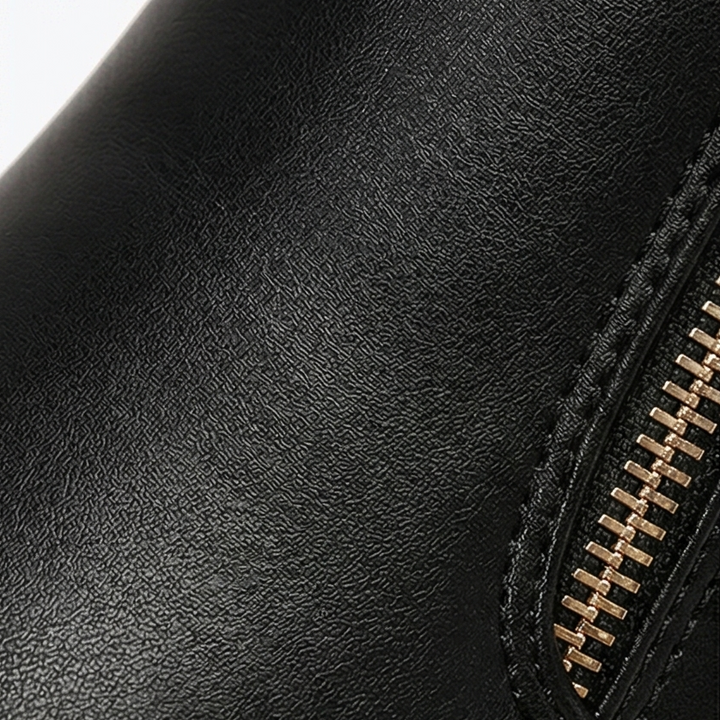 Close-up of the gold side zip and black textured upper on a platform ankle boot